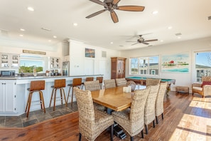 A spacious kitchen with a central island, a pool table, and a dining area with wicker chairs.