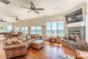 A spacious living room with a large sectional sofa, a fireplace, and a view of the ocean.