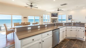 A kitchen with a large island, white cabinets, and a view of the ocean. - Beachfront, Pool, Spa, Pet Friendly, Elevator, Decks, fire pit, Games! (Saint George Island)