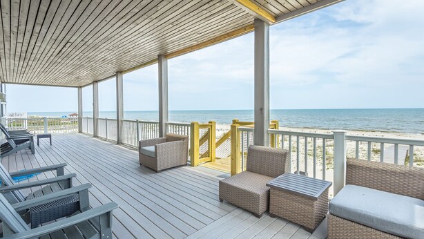A covered deck with wicker furniture and a view of the beach. - Beachfront, Pool, Spa, Pet Friendly, Elevator, Decks, fire pit, Games! (Saint George Island)