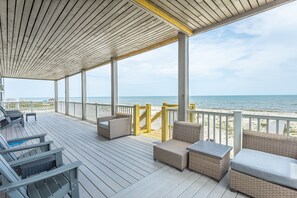 A covered deck with wicker furniture and a view of the beach. - Beachfront, Pool, Spa, Pet Friendly, Elevator, Decks, fire pit, Games! (Saint George Island)