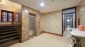 A hotel lobby with marble walls, a staircase, an elevator, and a hallway leading to another area. - Nam Hai Hotel (Hanoi)