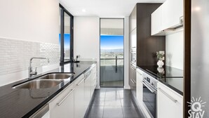 Uma cozinha moderna com uma janela ampla, eletrodomésticos de aço inoxidável e vista para a cidade.