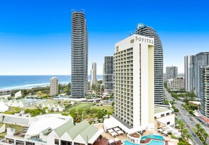 A high-rise hotel with multiple balconies, a pool area, and a view of the ocean. - The Wave - 3 Bedroom Ocean View Unit (Broadbeach)