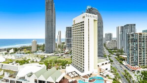 A high-rise hotel with a pool, surrounded by other tall buildings and a view of the ocean. - The Wave - 3 Bedroom Broadbeach Apartment (Broadbeach)