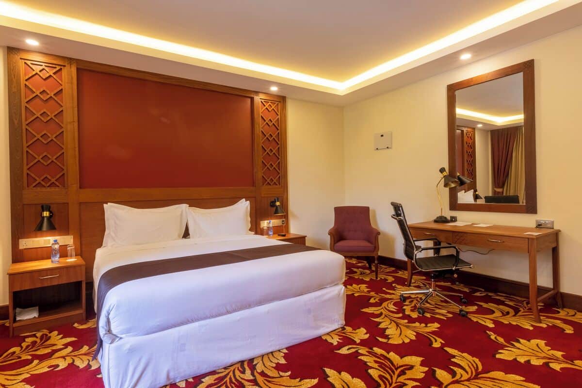 Une chambre d’hôtel avec un grand lit, un bureau, une chaise et un miroir.