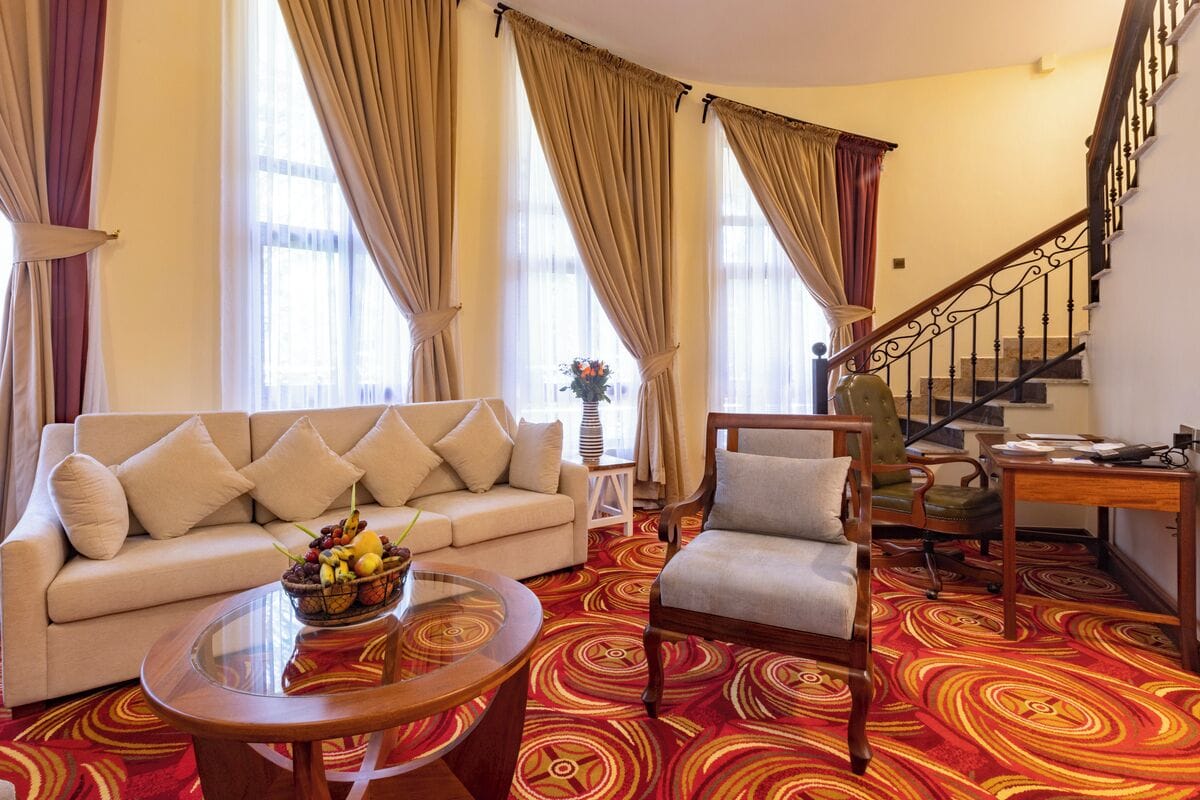 Un salon comprenant un canapé, un fauteuil, une table basse et un escalier.
