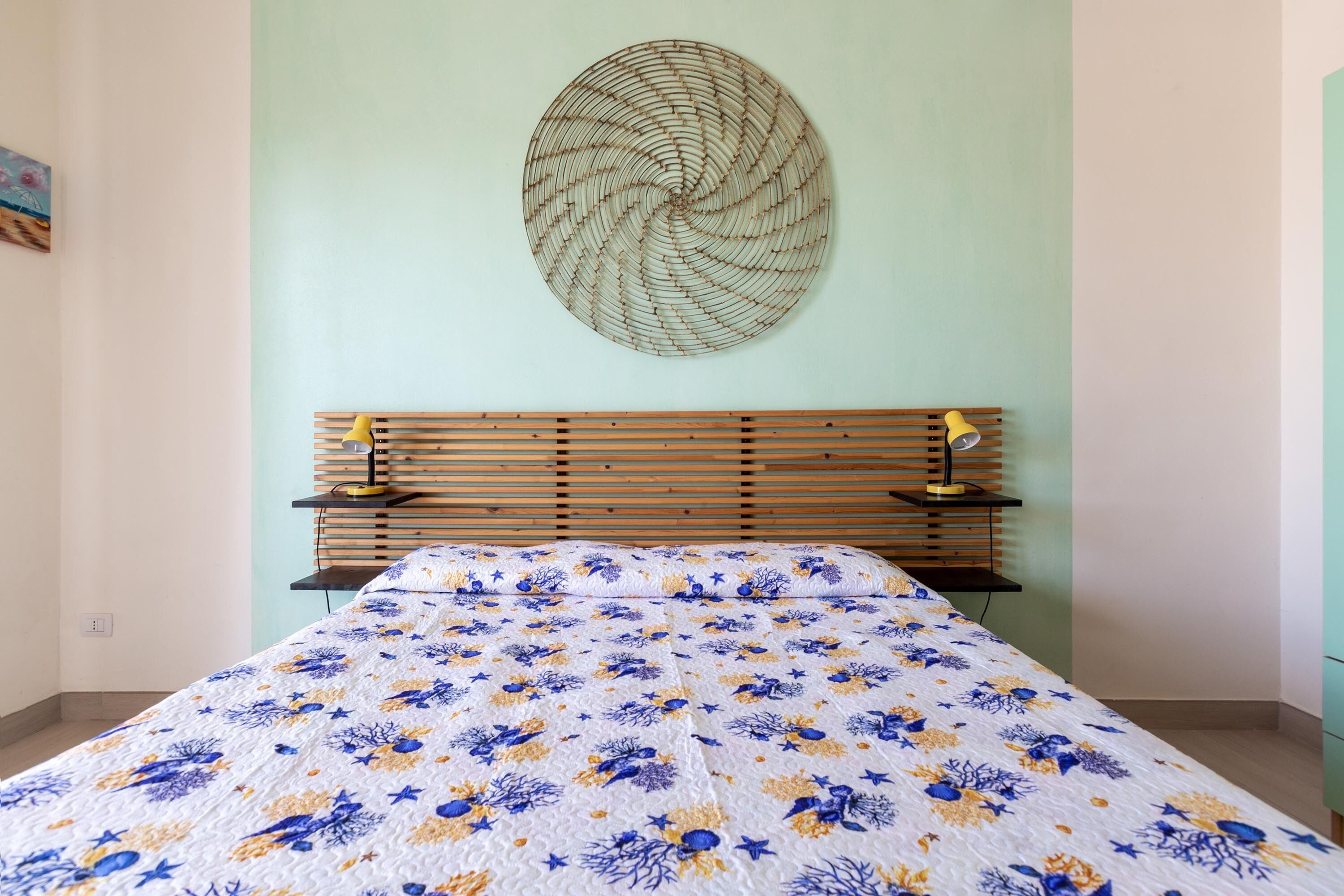 Een slaapkamer met een bed, een kunstwerk aan de muur en een houten hoofdbord.