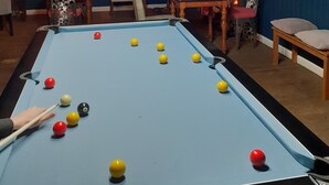 Ein Billardtisch mit Kugeln, eine Kristallleuchter und ein Kamin.