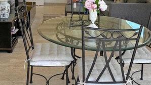 Un coin repas avec une table en verre et des chaises en métal, un canapé, un téléviseur et une porte dotée de panneaux en verre dépoli.