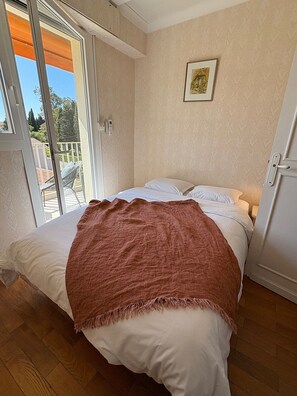 Une chambre à coucher avec un lit, une porte, une fenêtre et une vue sur l’extérieur.