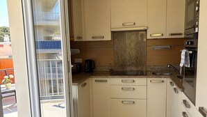 Une cuisine moderne dotée de portes coulissantes, d’un four encastré et d’un petit coin repas.