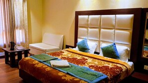 Una habitación de hotel con cama, una silla, una mesa y un espejo.