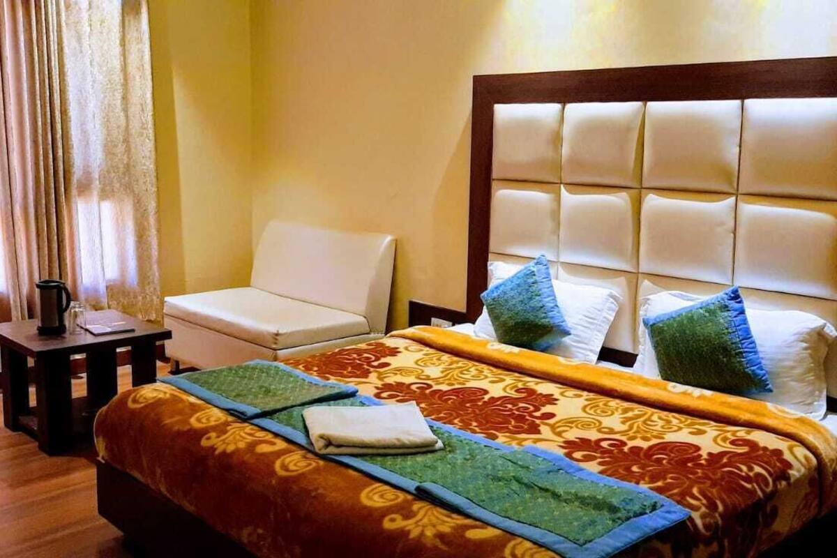 A hotel room with a bed, a chair, a table, and a mirror.