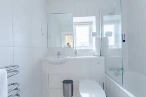 A modern bathroom with a white sink, toilet, and bathtub.