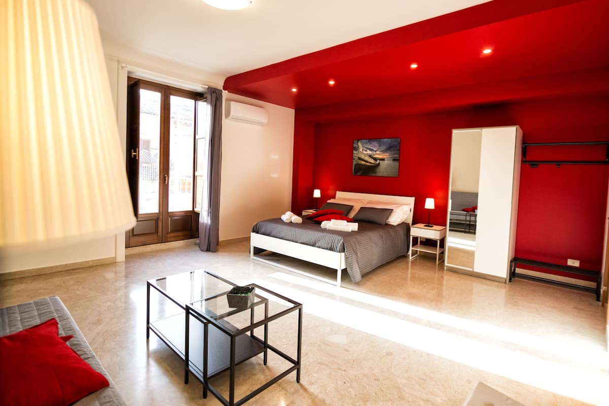 A modern bedroom with a bed, bedside tables, a glass table, and a wardrobe.