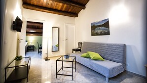 Una sala de estar con un sofá gris, una mesa de centro de vidrio, techo de madera y un cuadro en la pared.