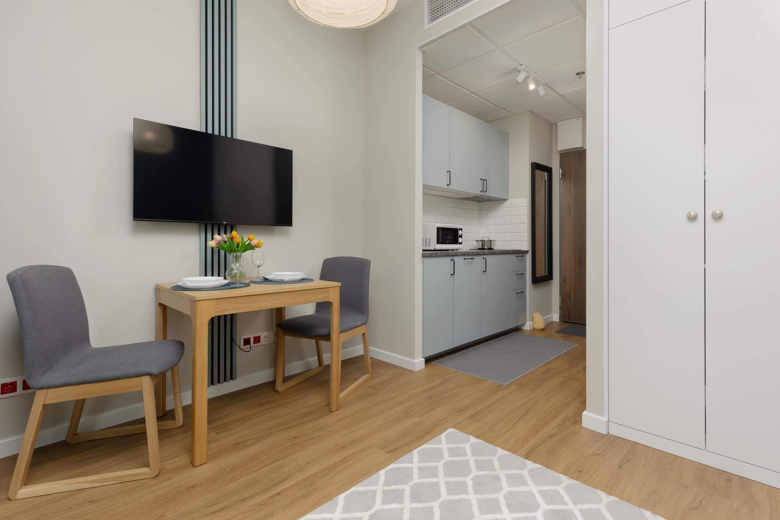 A modern kitchen with white cabinets, a microwave, and a wooden countertop.