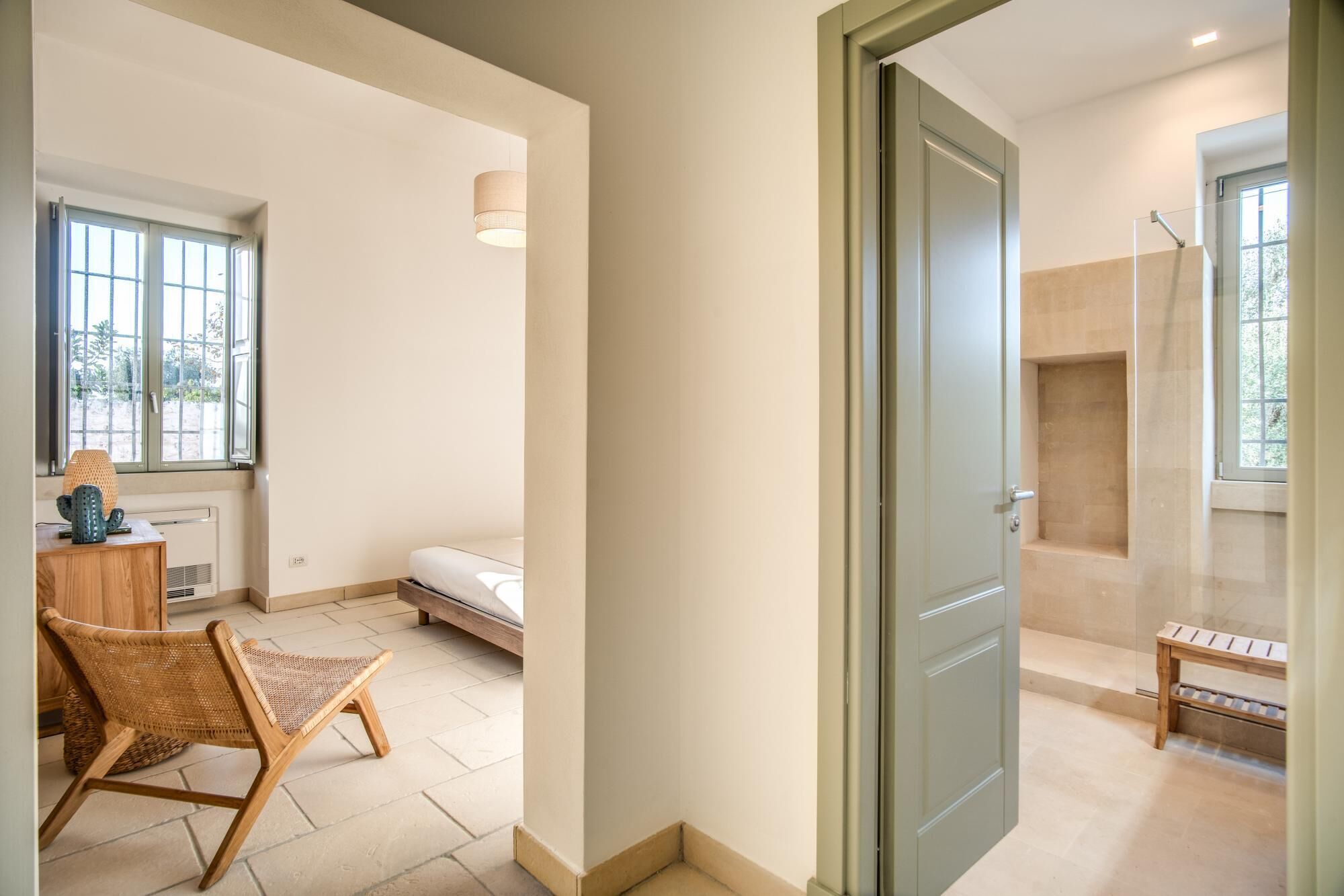 A bedroom with a bed, a chair, a bedside table, and a window.