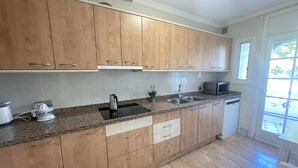 Una cocina con armarios de madera, encimera de granito, pileta, microondas y lavavajillas.