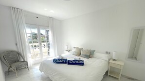 Una habitación de hotel con cama, una silla, una mesita de noche y un ventanal grande.