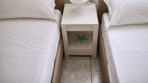 Een slaapkamer met twee bedden, een nachtkastje met een lamp en een zeester decoratie op het nachtkastje.