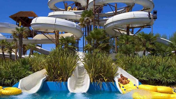 Een waterpark met meerdere glijbanen en een zwembad.