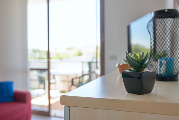 A small potted succulent on a wooden surface with a mesh container in the background. - Beautiful Cobalt Apartment, 100 Meters from the Ocean (Lido di Jesolo)