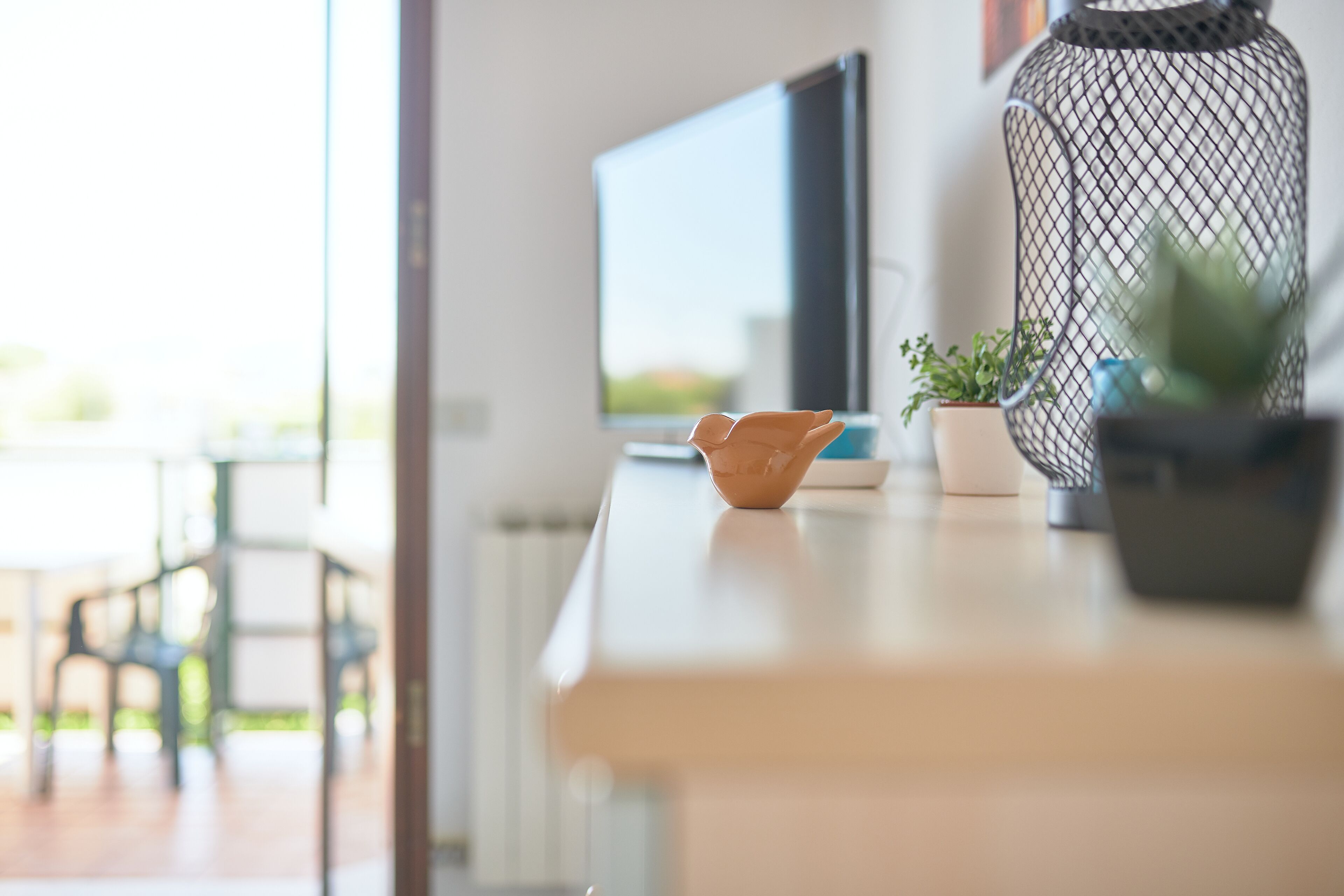 Una habitación moderna con un escritorio de madera, televisión y una planta en maceta.