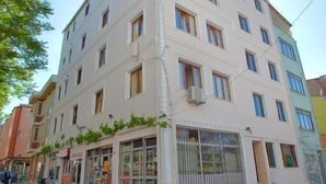 Un hotel de varios pisos con fachada plana, ventanas amplias y escaparates en la planta baja.