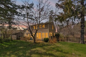 A two-story house with a front yard, a tree, and a fence.