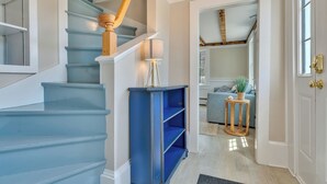 Un escalier aux marches bleues, une main courante en bois, une lampe et une bibliothèque.