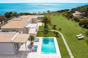 A rooftop terrace with a swimming pool, a well-maintained lawn, and a view of the sea. - Luxury villa with pool, beach front, Porto Ulisse (Ispica)
