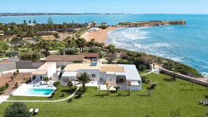 A coastal property with a swimming pool, multiple buildings, and a beach view. - Luxury villa with pool, beach front, Porto Ulisse (Ispica)