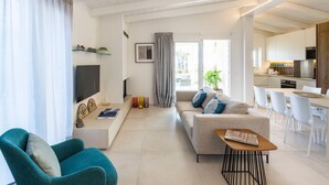 A modern living room with a sofa, a teal armchair, a coffee table, and a TV. - Luxury villa with pool, beach front, Porto Ulisse (Ispica)