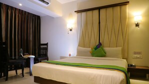 A hotel room with a large bed, a desk, a chair, and a nightstand. - Silver Paradise (Navi Mumbai)