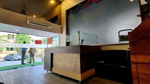 A modern interior with a reception desk, air conditioning units, and a view of the street outside. - Silver Paradise (Navi Mumbai)