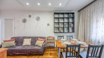 Un salon moderne comprenant un canapé, une table à manger, des chaises et une bibliothèque.