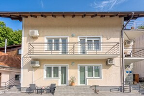 A two-story building with a balcony, air conditioning units, and a small outdoor seating area with chairs and a table. - Green Hill Zagreb Apartments (Zagreb)