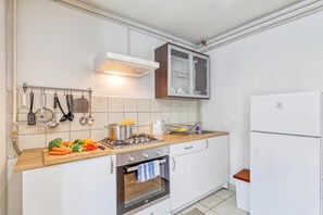 Una cocina compacta con horno integrado, estufa y refrigerador.