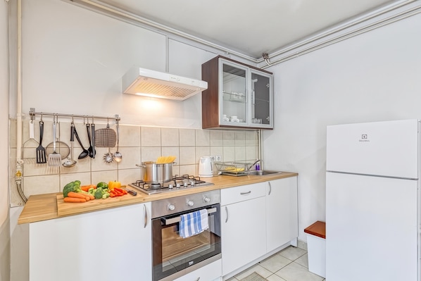 Una cocina compacta con horno integrado, estufa y refrigerador.