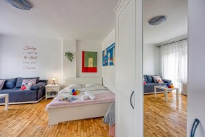 Une chambre moderne avec un lit, une table de chevet et un canapé. Un mur est décoré d’une citation inspirante et de deux tableaux abstraits.