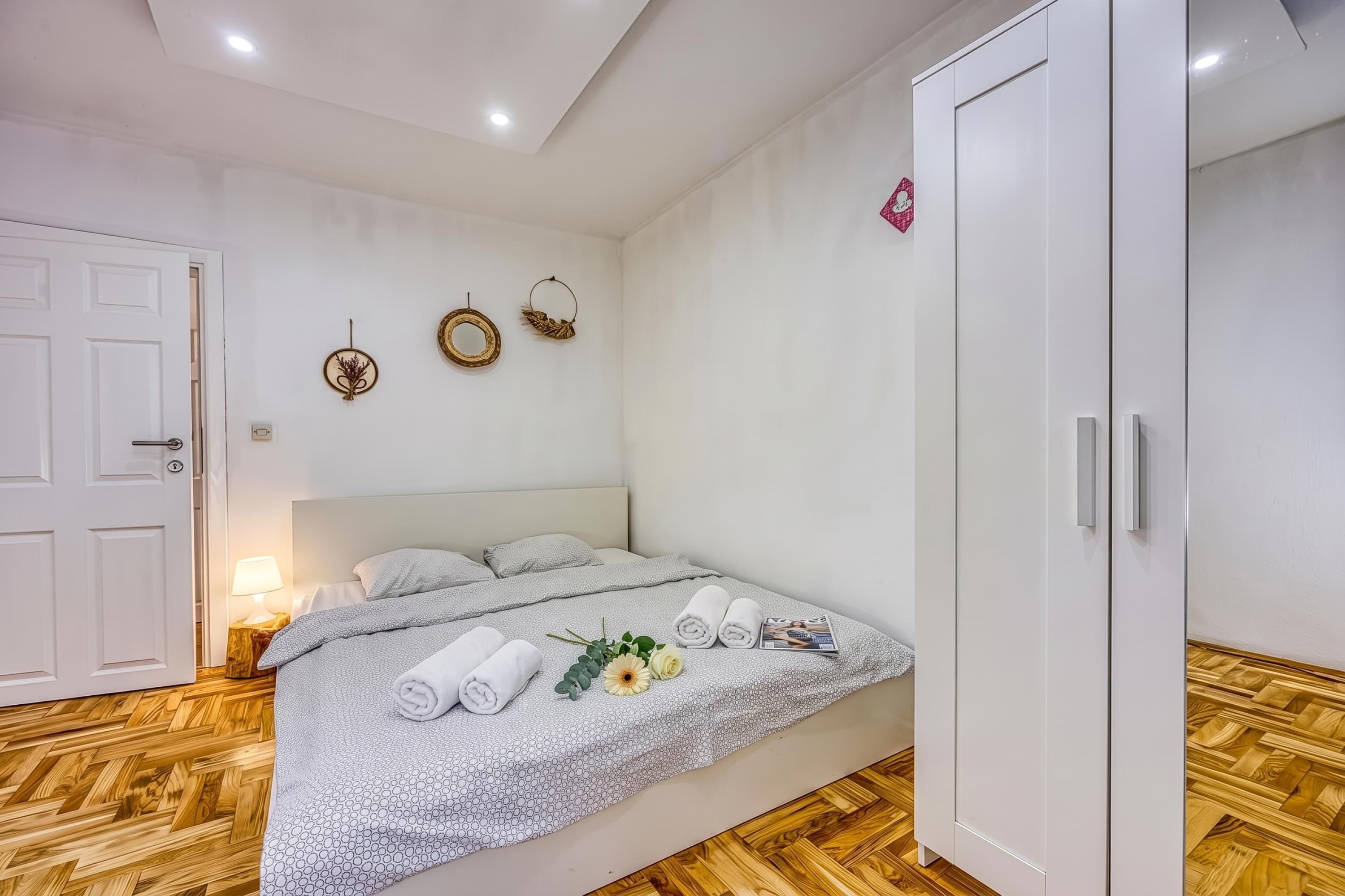 A hotel room with a bed, a wardrobe, and a wall with decorative items.