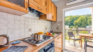 A modern kitchen with wooden cabinets, a gas stove, and a view of a balcony with outdoor furniture.