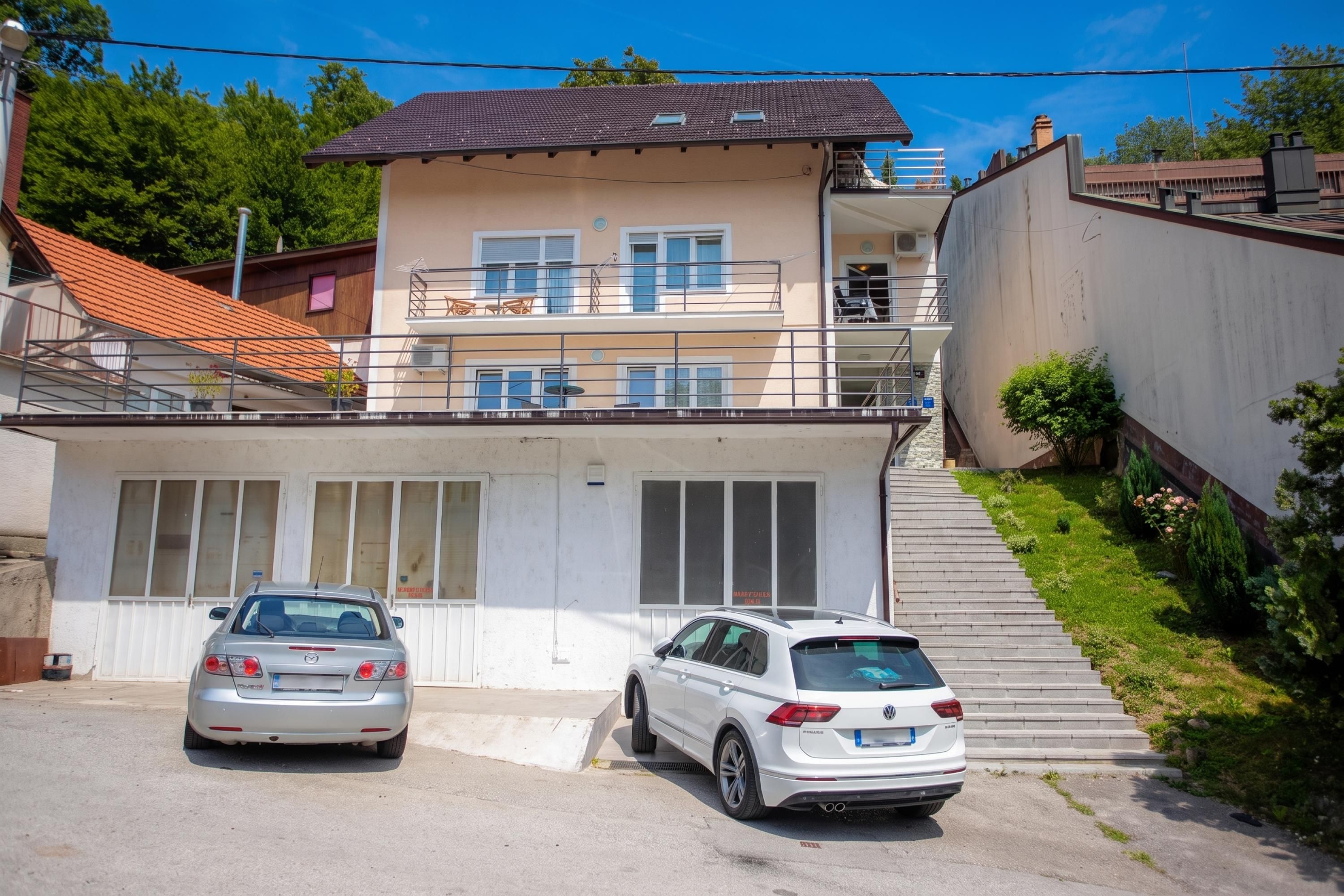A two-story building with a garage entrance and two parked cars.