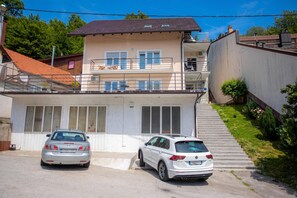 A two-story building with a garage entrance and two parked cars. - Green Hill Zagreb Apartments (Zagreb)