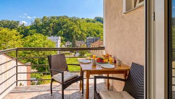 Un balcón con una mesa lista para el desayuno, con vistas a un paisaje verde.
