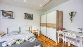 A modern bedroom with a bed, a desk, and two paintings on the wall.