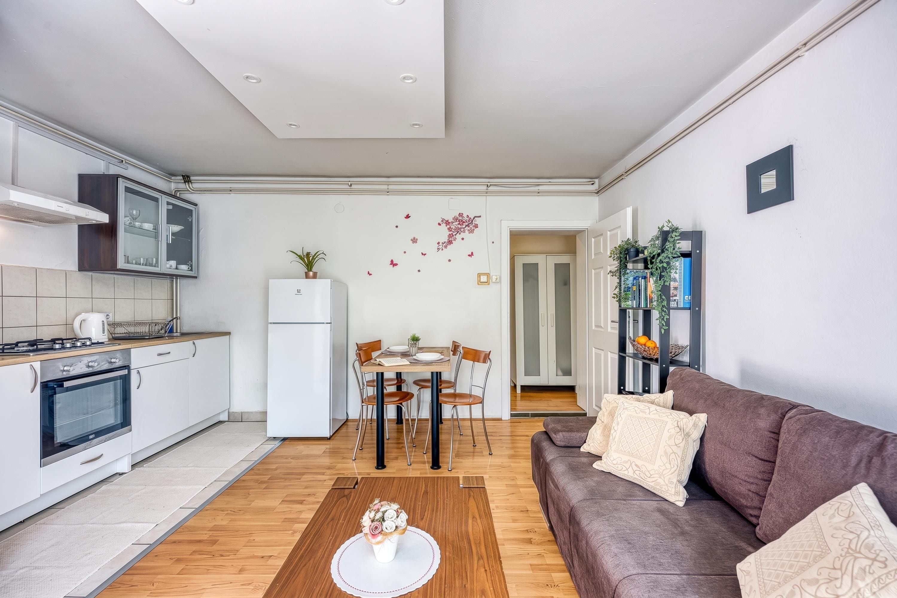 Un espacio habitable compacto con kitchenette, comedor y sofá.