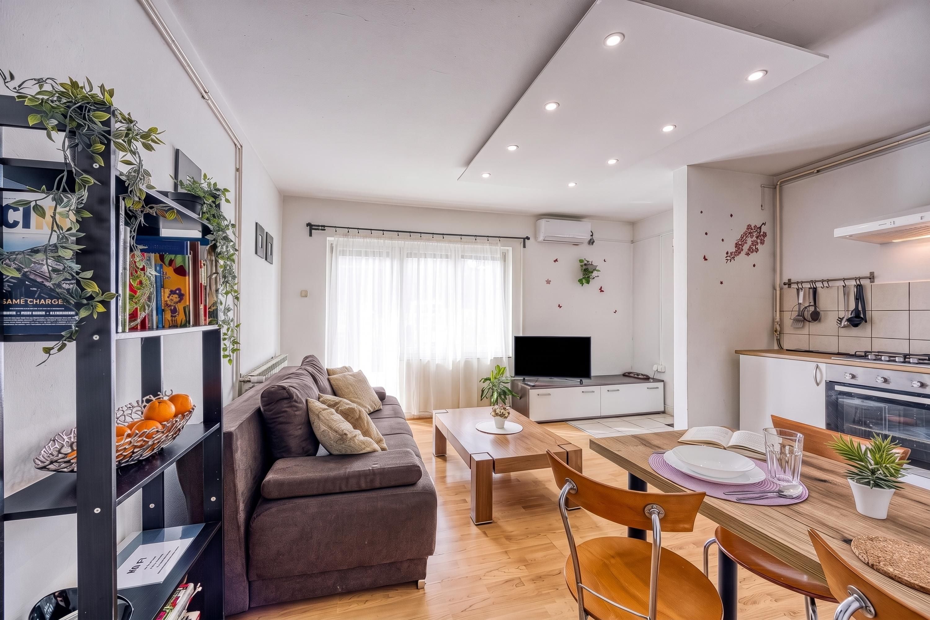 A modern living space with a sofa, dining table, and kitchen area.